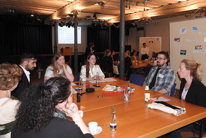 Das Bild zeigt Teilnehmerinnen und Teilnehmer des ersten Dialogforums in Mühldorf am Inn. Sie sitzen im städtischen Kulturzentrum an einem Tisch.