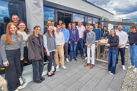 Studierende stehen bei schönem Wetter auf der Dachterrasse der BDO Wirtschaftsprüfungsgesellschaft mit Bernd Hacker und den Vortragenden der BDO 