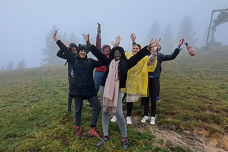 Gruppe steht mit Regenschirmen im Nebel auf dem Berg