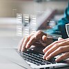 Bildfokus auf Hände, die auf der Tastatur eines Laptops schreiben