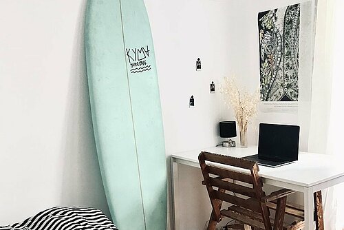 Student dorm with a surf board on the wall