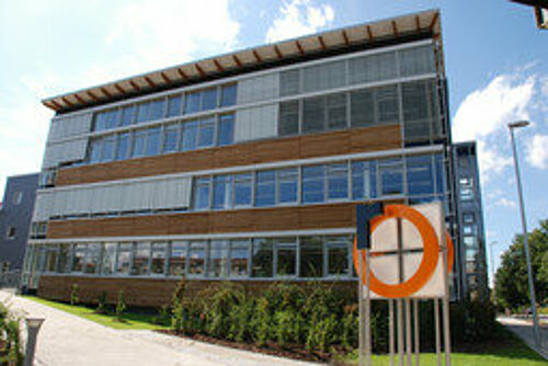 [Translate to English:] Campus Rosenheim S-Gebäude mit Logo im Vordergrund