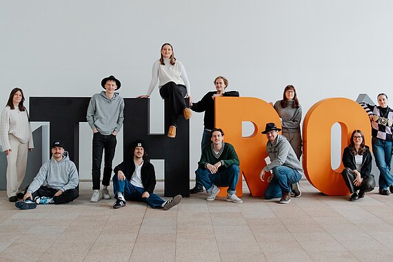 Studierende der TH Rosenheim stehen um menschengroße Buchstaben T, H, R und O
