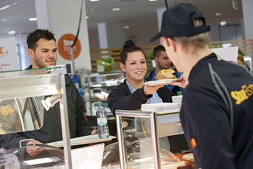 Auf dem Bild sind Studierende der TH Rosenheim an der Essensausgabe der Mensa am Campus in Rosenheim zu sehen. 