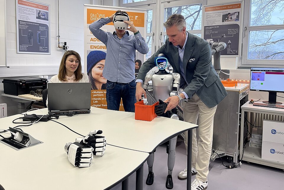 Das Bild zeigt Prof. Andreas Straube mit zwei Studierenden und dem humanoiden Roboter im Innovationslabor der TH Rosenheim.