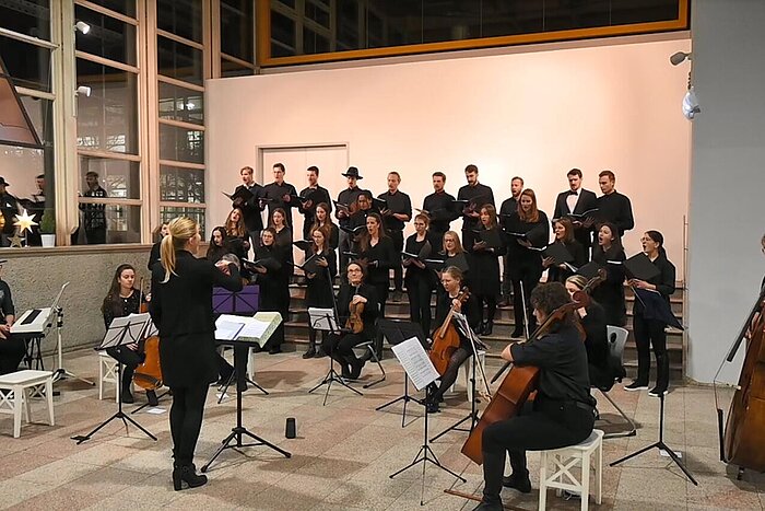 Auf dem Bild ist der Chor und das Orchester der TH Rosenheim bei einem Konzert im Foyer der Hochschule zu sehen.