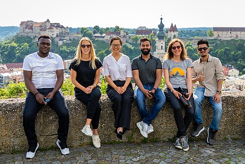 Internationale Studierende sitzen auf einer Mauer