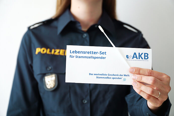 Person in Polizeiuniform mit Wattetupfer und Hinweis auf Typisierung der AKB in der Hands