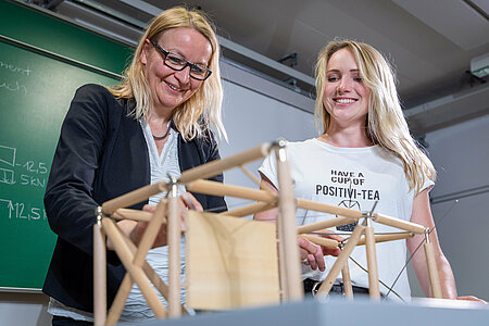Zwei Frauen stehen vor einem Fachwerk-Model aus Holz. 