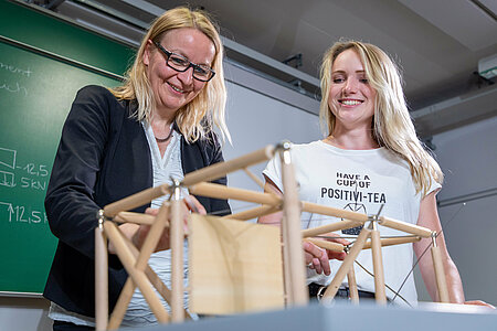Zwei Frauen stehen vor einem Fachwerk-Model aus Holz.