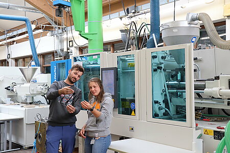 Studierende vor einer Spritzgießmaschine Leichtbauanwendung