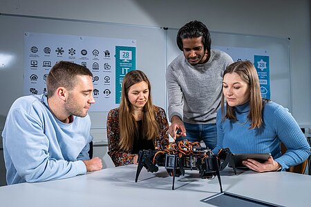Kleine Gruppe Studierender mit Roboter