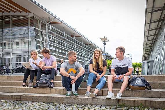 Gruppe Studierender sitzend auf Treppenstufen am Campus