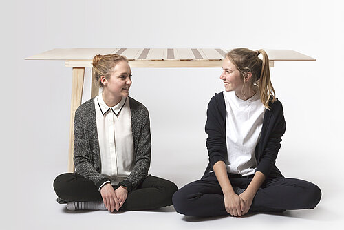 Zwei Studierende sitzen vor Ihrem Leichttischentwurf