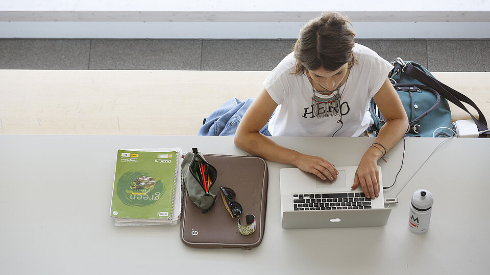Vogelperspektive auf Studentin, die mit Laptop an tisch lernt