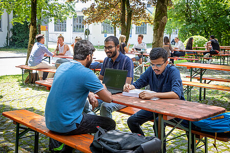 Drei Studierende der TH Rosenheim lernen im Biergarten der Rosenheimer Campusmensa.