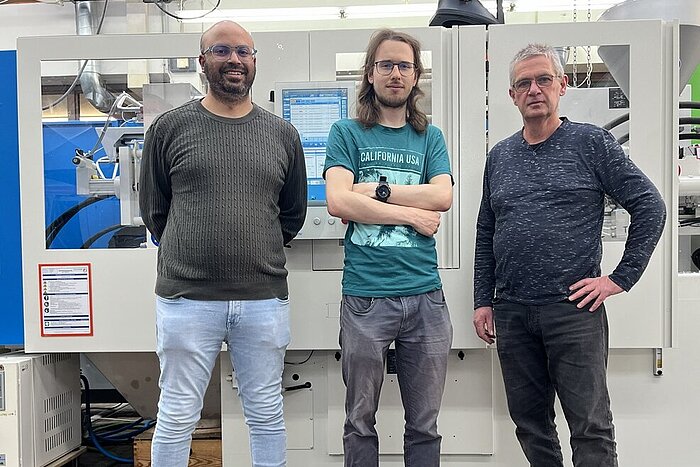 Das Bild zeigt die Studenten Abdul Pathan und Jephta Jaskolla mit Professor Peter Karlinger.