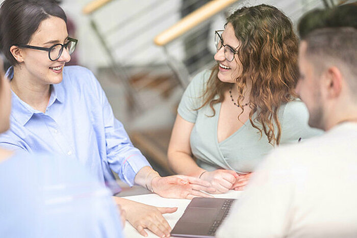 Zwei Studentinnen und Studenten bei der Gruppenarbeit an einem Tisch