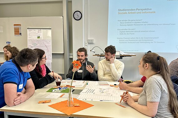 Eine Gruppe Studierender sitzt an einem Gruppentisch und arbeitet an einem Projekt 