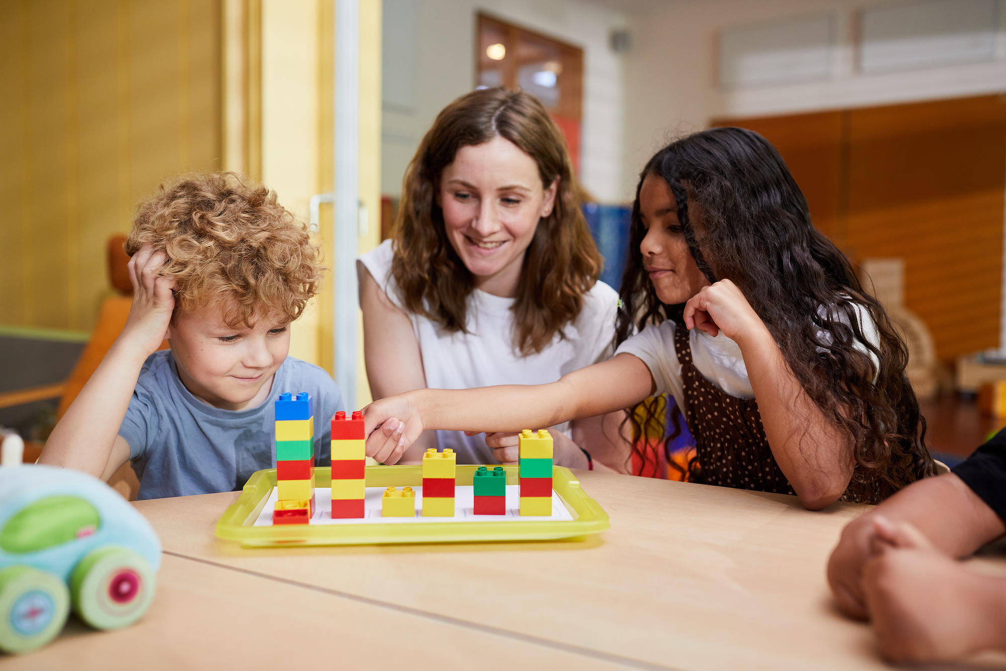 Erzieherin baut mit zwei Kindern Türme aus Duplosteinen